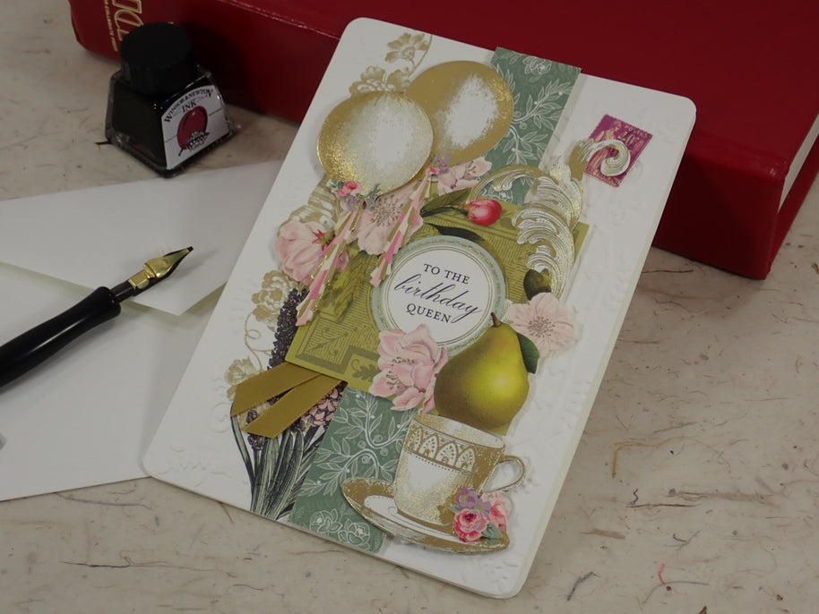 A handcrafted birthday greeting card with vintage-style collage elements including balloons, flowers, a teacup, and a central oval label reading 'to the birthday queen.' 