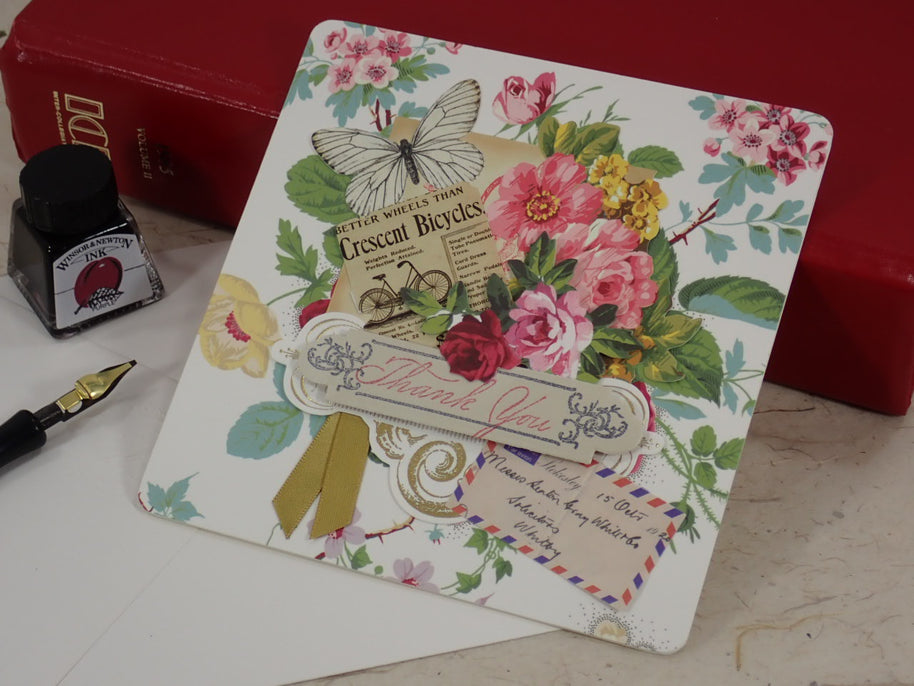 A handcrafted, Thank You card with vintage floral illustrations, a butterfly, a bicycle illustration, and layered paper embellishments.