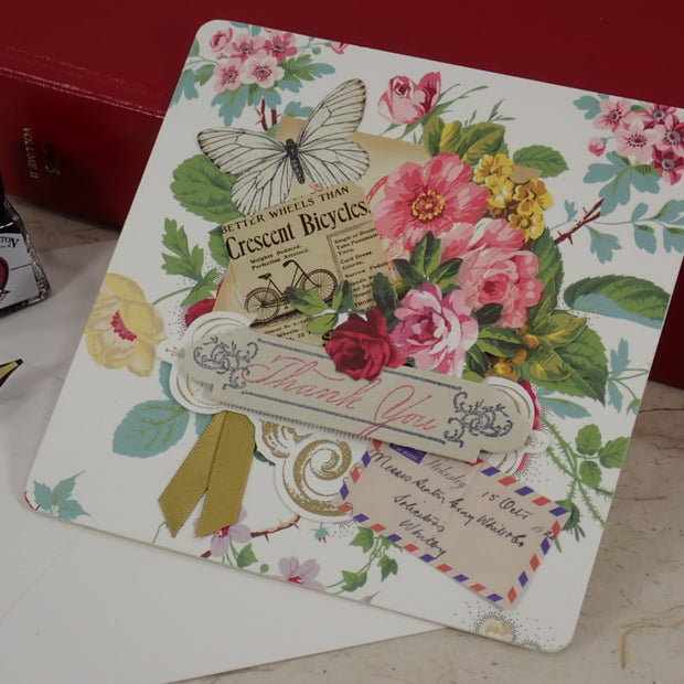A handcrafted, Thank You card with vintage floral illustrations, a butterfly, a bicycle illustration, and layered paper embellishments.