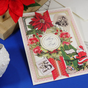 A handcrafted Christmas greeting card with red poinsettias, a Santa figure, and a central round label reading 'Merry and Bright,' styled on a blue surface with holiday props.