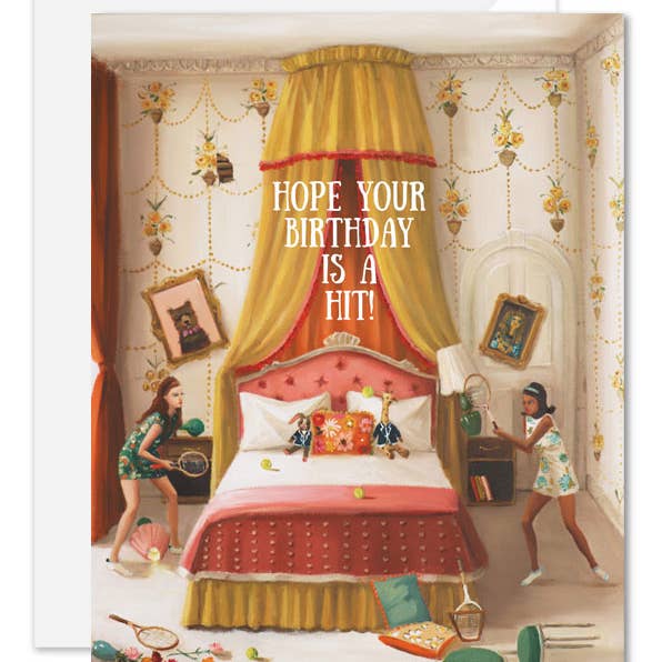 An artisan made, birthday greeting card featuring a whimsical illustration of a bedroom with a large canopy bed, floral wallpaper, and two girls playing with tennis rackets and balls. White text in the center reads, 'HOPE YOUR BIRTHDAY IS A HIT!'.