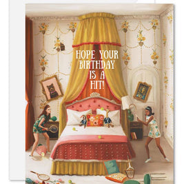 An artisan made, birthday greeting card featuring a whimsical illustration of a bedroom with a large canopy bed, floral wallpaper, and two girls playing with tennis rackets and balls. White text in the center reads, 'HOPE YOUR BIRTHDAY IS A HIT!'.